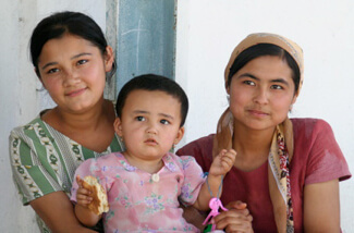 Mary E. Frederickson, Young weavers with a "lap baby" on break in the factory courtyard, Uzbekistan, 2006. Mary E. Frederickson, Young weavers with a "lap baby" on break in the factory courtyard, Uzbekistan, 2006.
