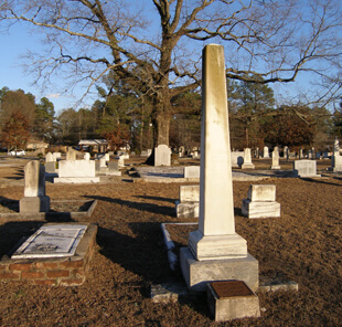 Ellen Schattschneider, Bishop Andrew memorial obelisk in the Andrew family plot (foreground) and the Kitty Tablet at the base of the Gateway Oak (background), Oxford, Georgia, 2005.  Ellen Schattschneider, Bishop Andrew memorial obelisk in the Andrew family plot (foreground) and the Kitty Tablet at the base of the Gateway Oak (background), Oxford, Georgia, 2005.