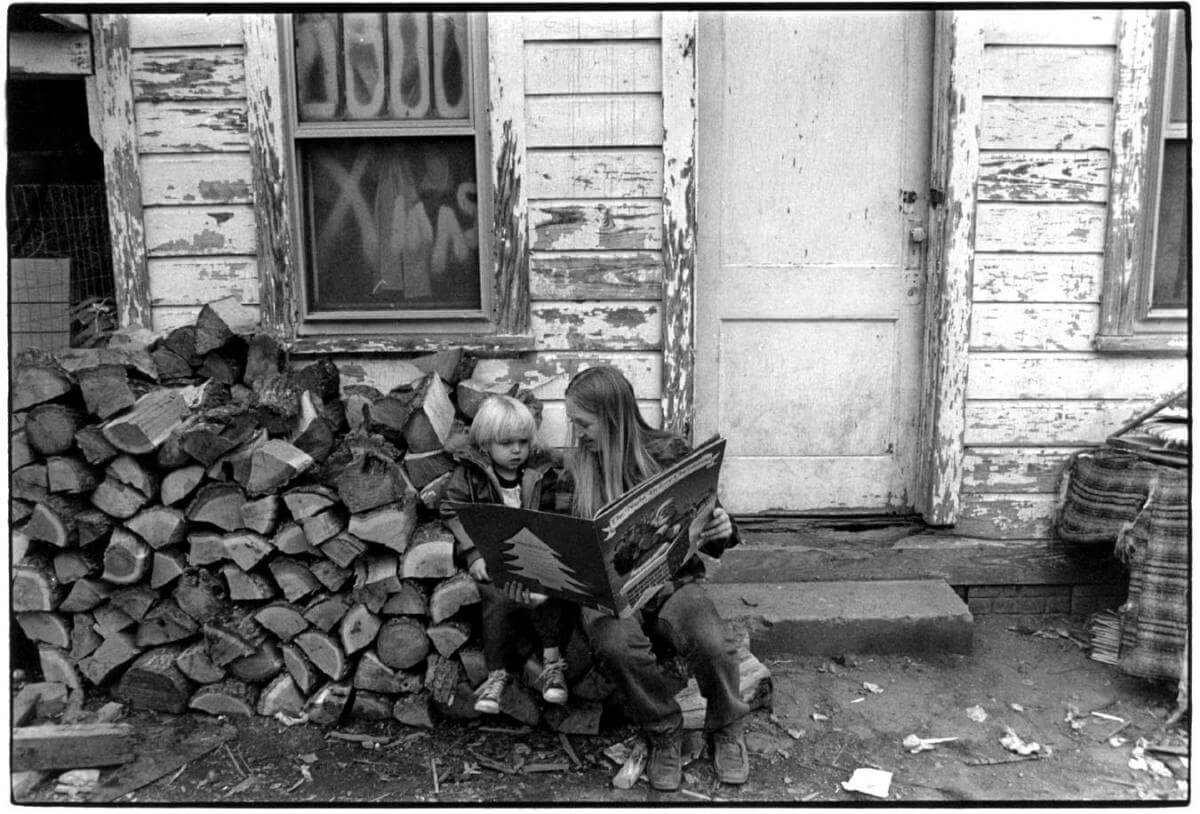 A mother who is part of the Head Start Program reading to her child in front of their home, Walnut, North Carolina. Photo courtesy of Rob Amberg.