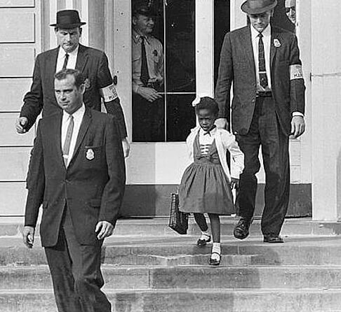 US marshals escort Ruby Bridges at William Frantz Elementary School, New Orleans, Louisiana, November 14, 1960. Photograph by unknown creator. Courtesy of Wikimedia Commons. Image is in public domain.