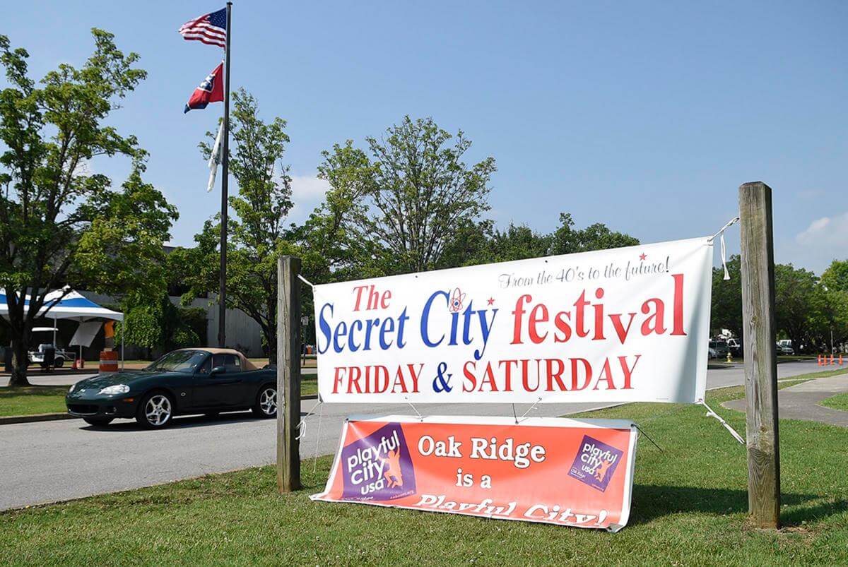 A car drives past a banner advertising the Secret City Festival, Oak Ridge, Tennessee, June 11, 2015. Photograph by Adam Lau. Courtesy of Knoxville News Sentinel.