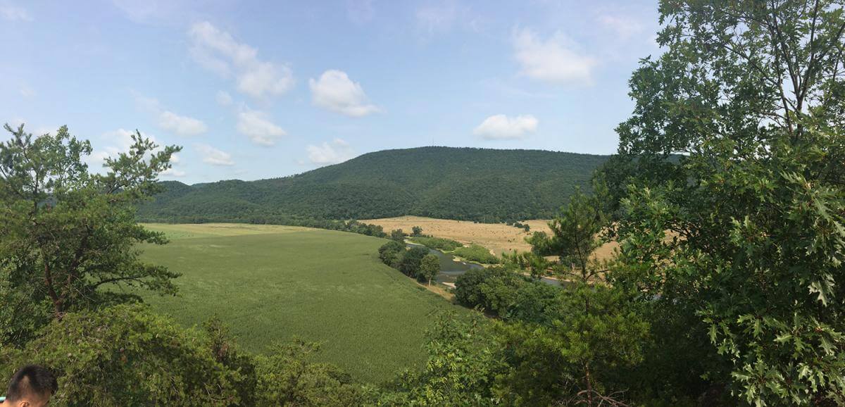 Breakneck Scenic Overlook, Romney, West Virginia, July 29, 2014. Photograph by Justin Wilcox. Courtesy of Wikimedia Commons. Creative Commons license CC BY-SA 4.0. Pancake family land appears in the lower section of the photo. A photograph depicting a landscape of rolling hills and trees in Romney, West Virginia.