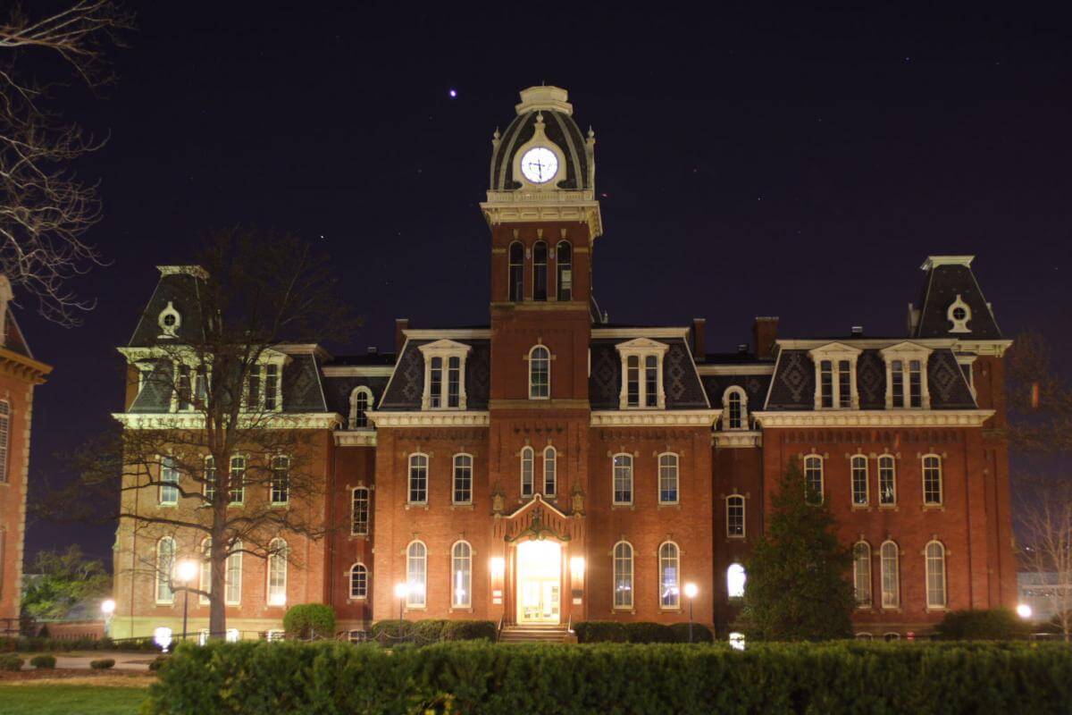 Nighttime shot of Woodburn Hall on the West Virginia University Campus, Morgantown, West Virginia, April 22, 2007. Photograph by Flickr user J. Robinson. Creative Commons license CC BY-NC-ND 2.0. Photograph of a large, well-lit brick university building with a clock tower at night.