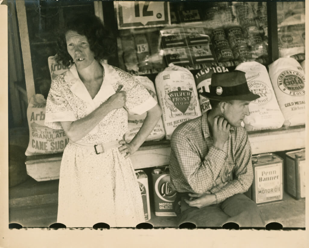 "Main Street at Kingwood, West Virginia," Kingwood, West Virginia, ca. June 1935. Photograph by Walker Evans. Courtesy of the J. Paul Getty Museum, Los Angeles, California. Image is part of Getty's open content program. The image illustrates the commonly circulated depiction of people from Appalachia. Sepia-toned photograph depicting a middle-aged man and woman sitting in front of a grocery store, looking away from the camera.