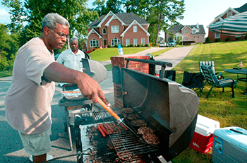 Annual block party, Stone Mountain, Georgia, July 18, 2004. James Giffin Jr. grills burgers and dogs in Southland Subdivision while his father James Giffin Sr. looks on. Both are originally from Chicago. Southland is a predominately African American middle to upper middle class neighborhood. Photograph by HIP Incorporated © 2004. Annual block party, Stone Mountain, Georgia, July 18, 2004. James Giffin Jr. grills burgers and dogs in Southland Subdivision while his father James Giffin Sr. looks on. Both are originally from Chicago. Southland is a predominately African American middle to upper middle class neighborhood. Photograph by HIP Incorporated © 2004.
