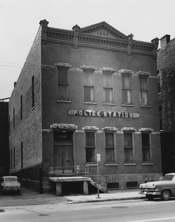 Old Police Station, New Orleans, Louisiana, 1963. Photoprint by Clarence John Laughlin. Courtesy of The Clarence John Laughlin Archive, The Historic New Orleans Collection. Black and white photograph of a two-story brick building with a large sign reading "Police Station."