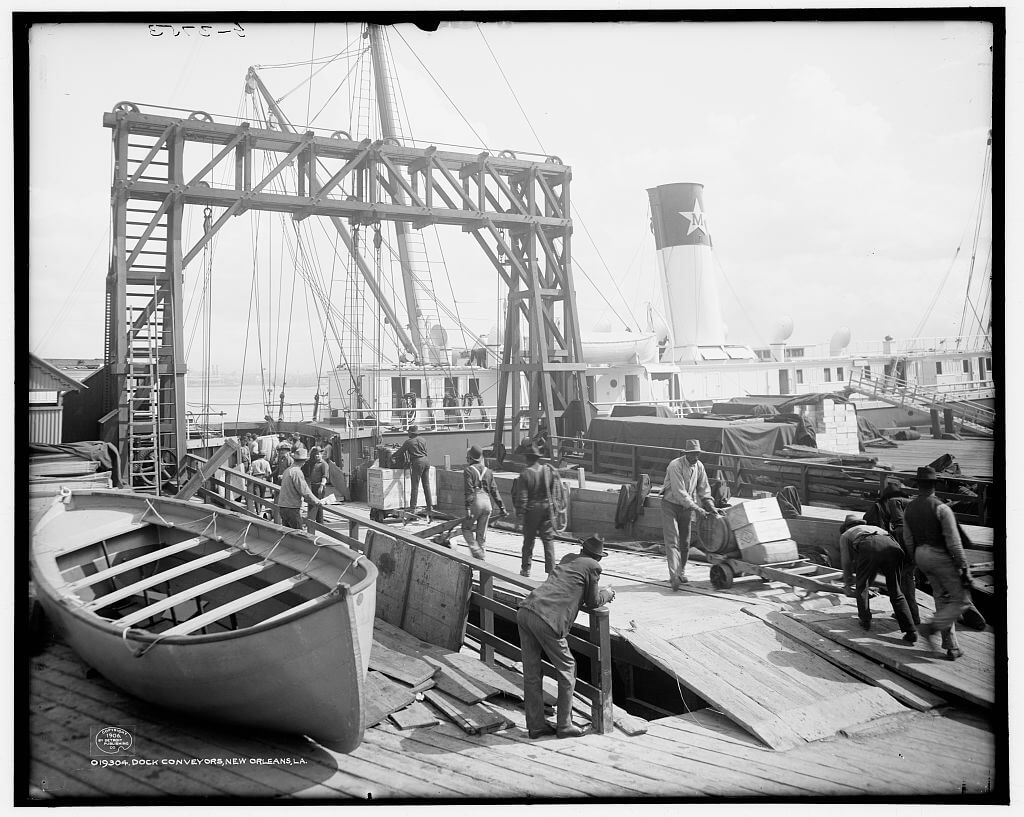 Dock Conveyors, New Orleans, Louisiana, ca. 1906. Photograph by Detroit Publishing Company. Courtesy of Library of Congress Prints and Photographs Division, Washington, DC, loc.gov/pictures/item/2016805993. Black and white photograph of men working on a dock.