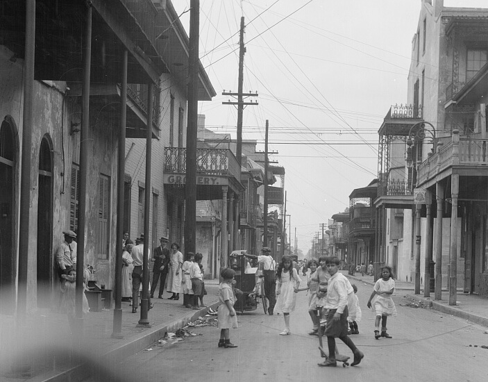 Children in a French Quarter street, New Orleans, Louisiana, ca. 1920–1926. Photograph by Arnold Genthe. Courtesy of Library of Congress Prints and Photographs Division, Washington, DC, loc.gov/pictures/item/agc1996001404/PP. Black and white photograph of children walking and playing in a street.