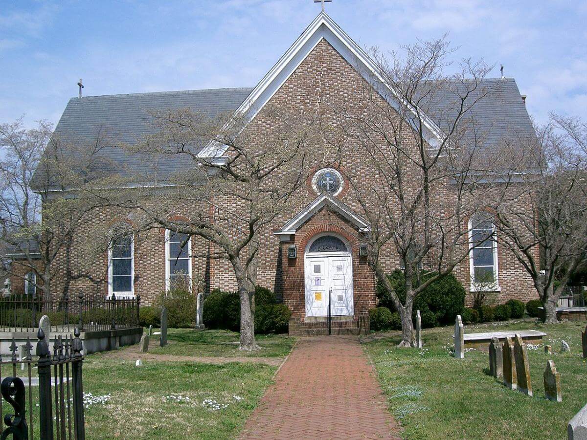 South side of St. John's Episcopal Church, St. John's Episcopal Church, Hampton, Virginia, March 26, 2007. Photograph in public domain. Courtesy of Wikimedia Commons. Creative Commons license CCO 1.0. Established in 1610, St. John's is the oldest English-speaking parish in continuous existence in the United States. Photograph of the south side of St. John's Episcopal Church, an old brick building with weathered gravestones in the front yard.
