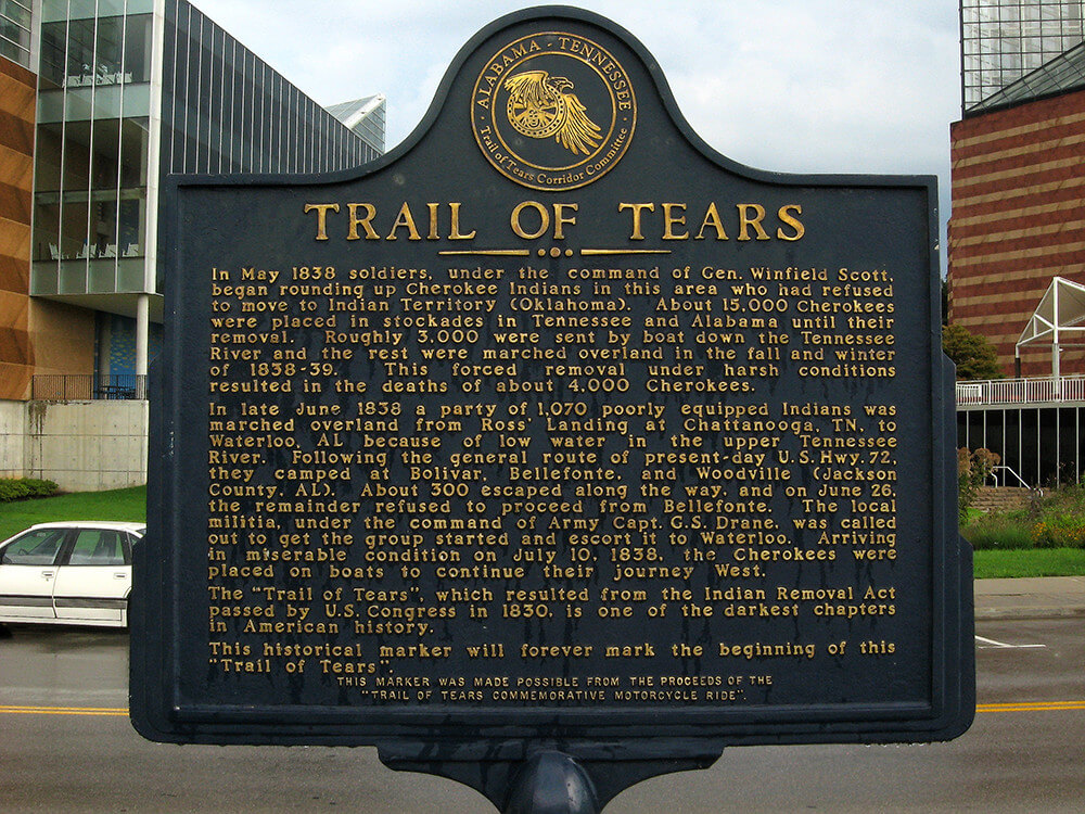 Trail of Tears historical marker, Chattanooga, Tennessee, August 19, 2009. Photograph by Flickr user BitHead. Creative Commons license CC BY-NC-SA 2.0. Photograph of the Trail of Tears historical marker, which describes the history of the trail of tears in golden text embossed on a black background.