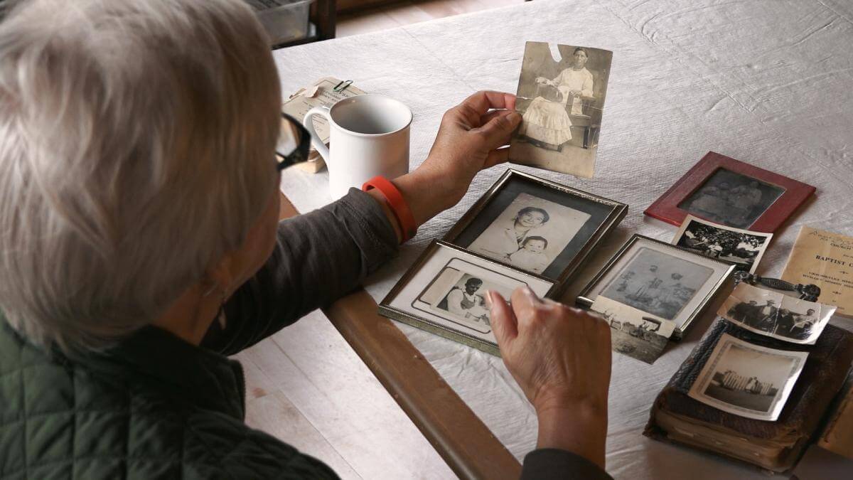 Rosemary McCombs Maxey looks at family photographs, Dustin, Oklahoma, 2015. Screenshot from Hearing the Call courtesy of Southern Spaces. Rosemary McCombs Maxey looks at family photographs, Dustin, Oklahoma, 2015. Screenshot from Hearing the Call courtesy of Southern Spaces.