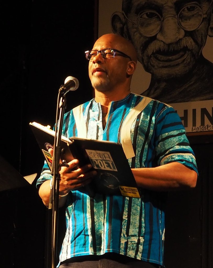 Frank X Walker reads from a book into a microphone.