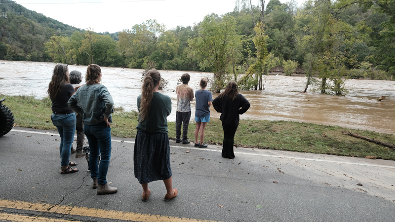 People looking at the raging French Broad River during Hurricane Helene.