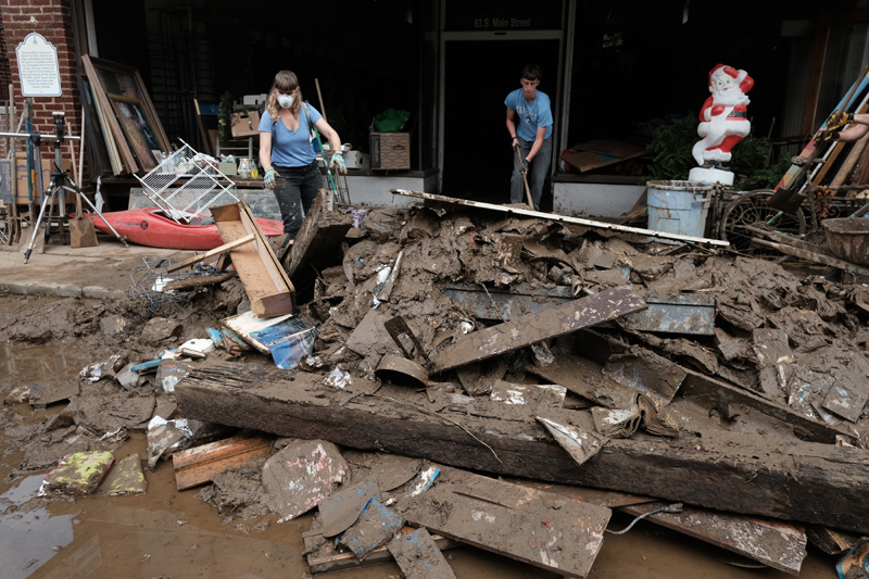 Couple removing debris from used bookstore in Marshall, North Carolina, after Hurricane Helene.