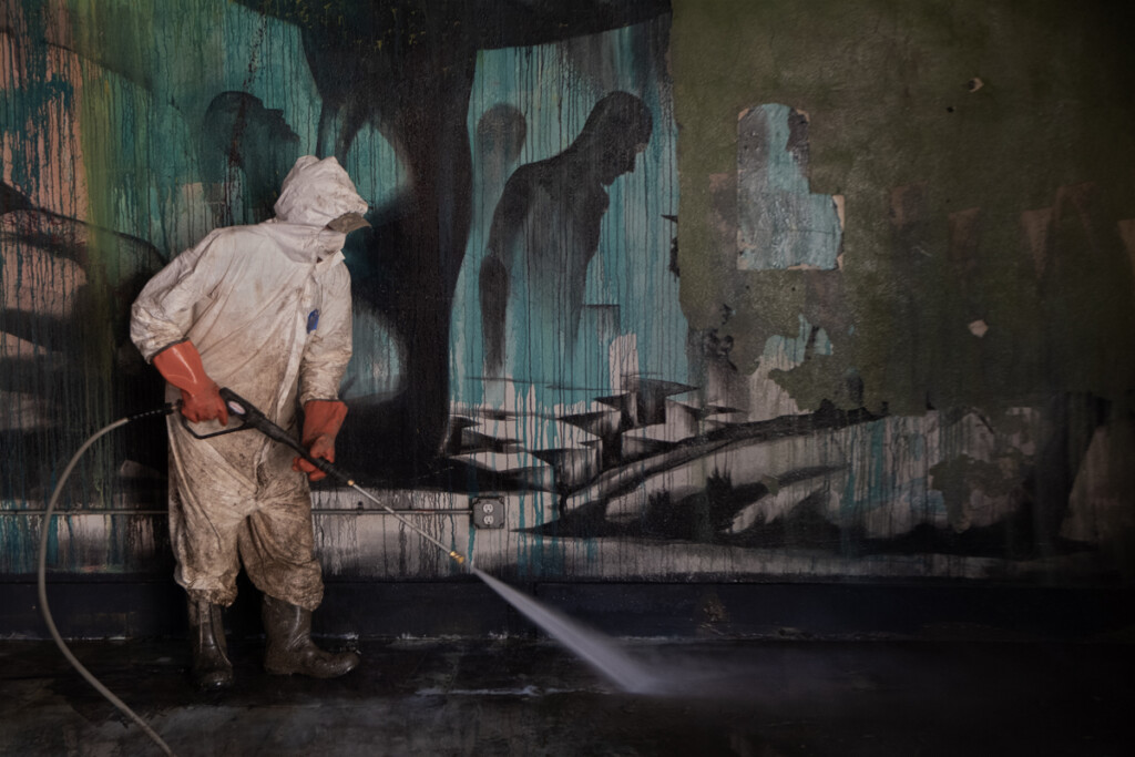 Unidentified man pressure washing art gallery in Marshall, North Carolina, after flooding from Hurricane Helene.
