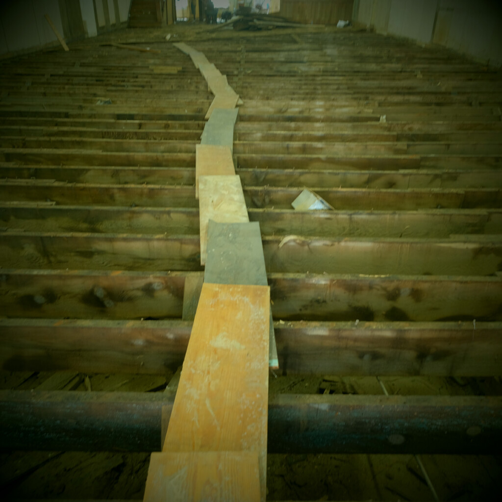 Floor joists in Penlands Department store after flooring has been removed and piled flooring in street. Main street, Marshall, after Hurricane Helene.